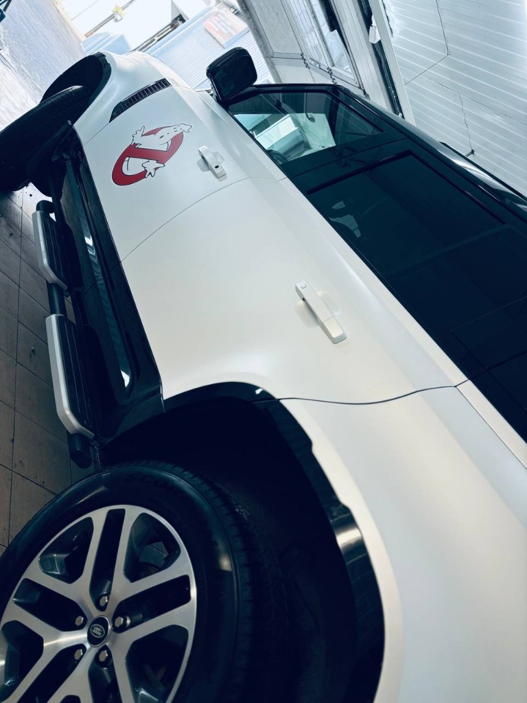 Land Rover Defender в белом сатине — боковой ракурс с логотипом Ghostbusters